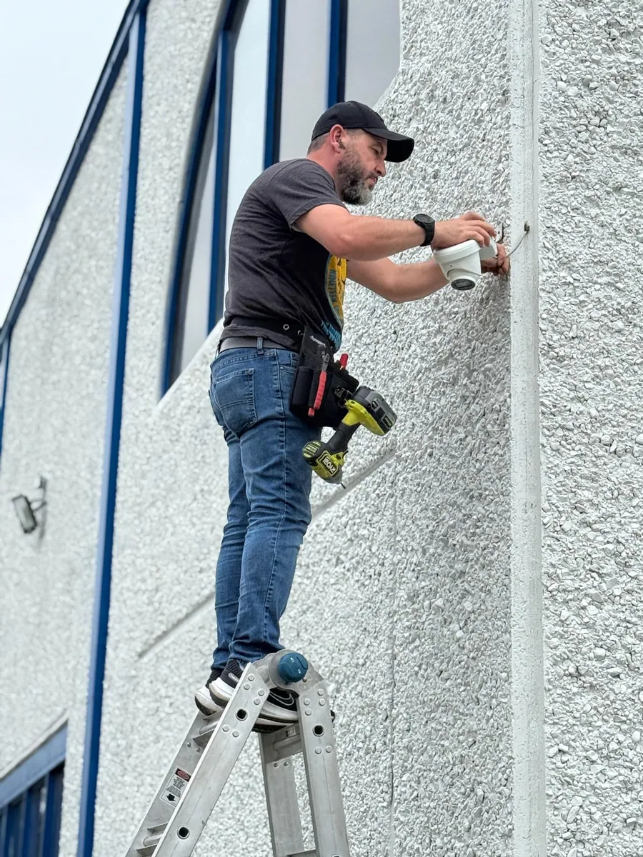 Technician drilling a camera mount into a stucco wall